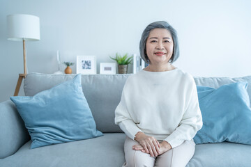 Senior older woman smile and looking at camera in living room at home.