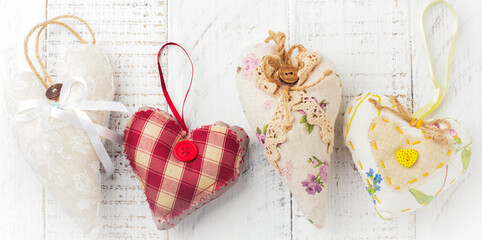 Group of festive hearts from various materials, cloth, wool, wooden, on white wooden background. Selective focus. Vintage Valentine card. Top view. Place for text