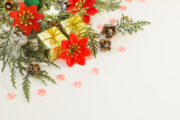 Christmas border with snowy pine leaves,gift boxes and christmas decorations on white surface with copy space