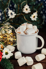 Christmas drink hot chocolate with marshmallows at festive illuminated decoration. Selective focus