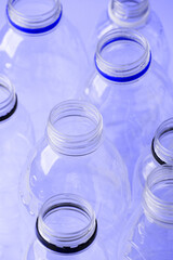 Set of diverse used empty water plastic bottles without caps on purple violet trendy background. Concept of recycle plastic pakaging, reuse industry, zero waste, eco-friendly, color of year 2022