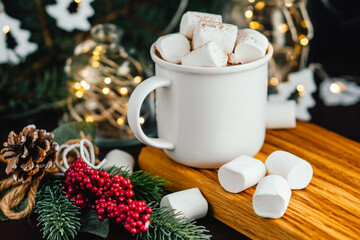 Christmas drink hot chocolate with marshmallows at festive illuminated decoration. Selective focus