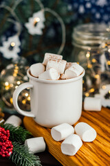 Christmas drink hot chocolate with marshmallows at festive illuminated decoration. Selective focus