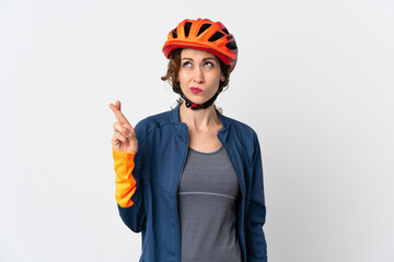 Young cyclist woman isolated on white background with fingers crossing and wishing the best