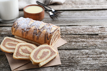 Tasty cake roll with cream on wooden table, space for text