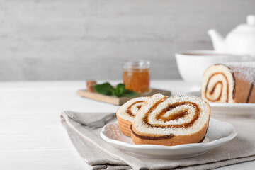 Tasty cake roll with jam on white wooden table, space for text