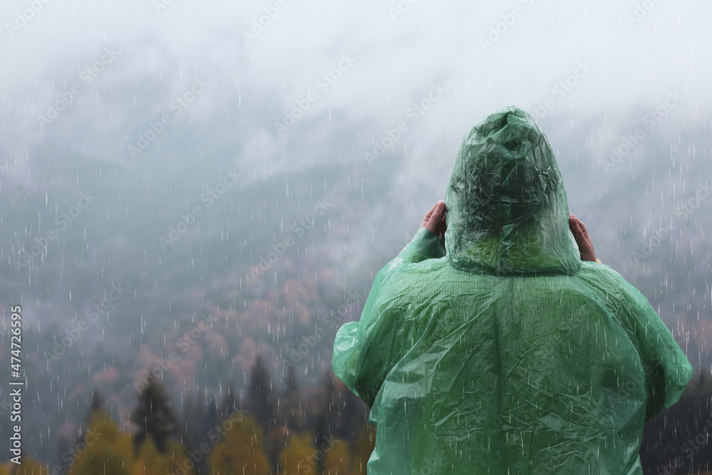 Sticker woman in raincoat enjoying mountain landscape under rain, back view