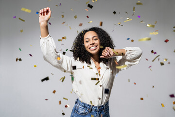 Beautiful young woman at celebration party with confetti falling everywhere on her. Birthday or New...