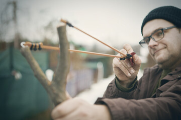 Adult man in winter time outdoor with home made slingshot