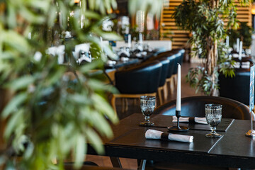 setting table, luxury restaurant interior in black shades with a lot of vegetation