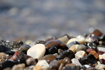 Wet pebble stones on blurred background of sea waves. Beach vacation concept