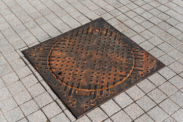 Old rusty square manhole on the road