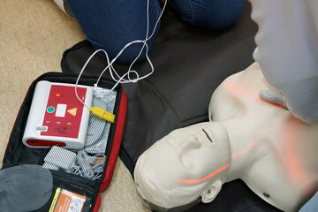 Chest compressions by a student on a simulation dummy during basic life support with an automatic external defibrillator. Simulation training scenario - obrazy, fototapety, plakaty
