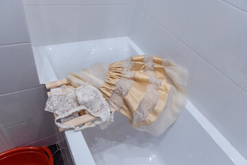 An elegant evening dress and beautiful lace underwear is lying in the bathroom, needs washing after a festive party