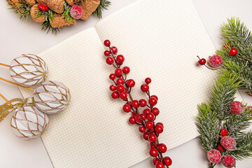 New Year's table with a clean notebook, rowan, fir branches and Christmas decorations.