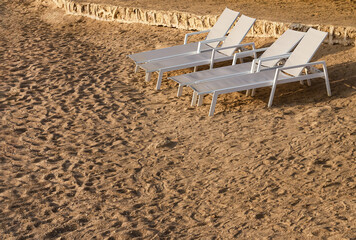 four isolated sun loungers on a deserted beach.Natural background with beach furniture and no people