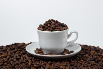 Coffee beans on a white background. A coffee cup full of coffee beans. Large serving of caffeine