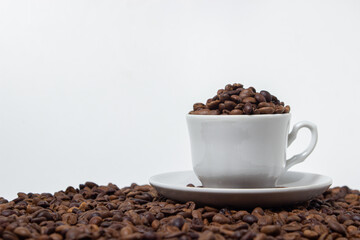 Coffee beans on a white background. A coffee cup full of coffee beans. Large serving of caffeine