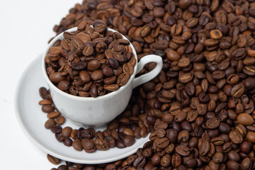 Coffee beans on a white background. A coffee cup full of coffee beans. Large serving of caffeine