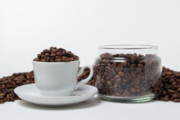Coffee beans on a white background. A coffee cup full of coffee beans. Large serving of caffeine
