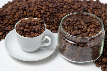 Coffee beans on a white background. A coffee cup full of coffee beans. Large serving of caffeine