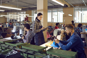 Portrait of female quality controller master check male shoemaker work. Professional control at shoe production factory. Workshop interior with workers make fashion footwear using industrial equipment - obrazy, fototapety, plakaty
