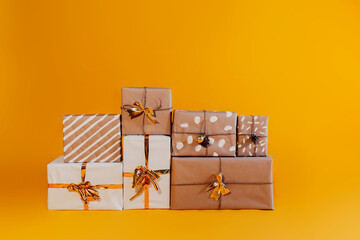 Kraft paper gifts on orange background. Many Christmas presents in kraft paper on orange background.