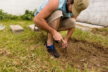 Hombre preparando el suelo en el jardín para la construcción de un fogón con piedras naturales. Concepto de bioconstrucción, herramientas de  jardinería, ambiente al aire libre, aprovechar, reciclado