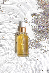 Amber bottle of lavender essential oil. Flat lay concept. Light background with water waves.
