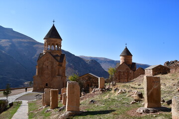 View of the monastery in the mountains. Two stone churches against the backdrop of high mountains and blue sky.