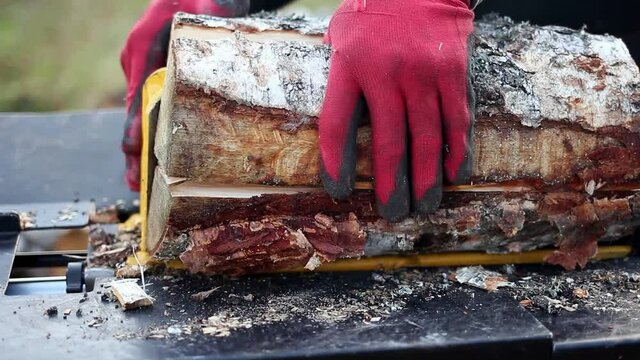 Close up of male hands chopping birch firewood on a hydraulic wood splitter. Sawmill. Birch firewood for fireplac
