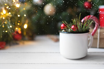 Christmas mug with red balloons, Christmas tree branches and lollipops on white table. Authentic Christmas photo. Preparation for the holiday. Advent. Cozy Holiday at home
