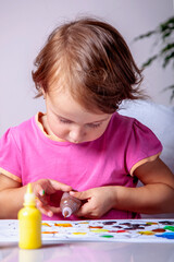 Portrait of cute little girl drawing with colorful paint. Beautiful adorable child painting at table.