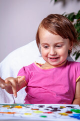 Portrait of beautiful little girl enjoying her painting. Vertical image.