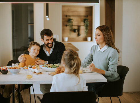 Young happy family talking while having lunch at dining table