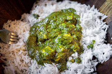 Macro closeup of Indian meal dish of palak paneer cottage cheese with pureed spinach with basmati...