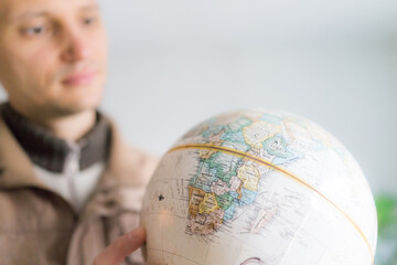 Young man holding looking at vintage retro old brown globe world map with equator, Africa continent
