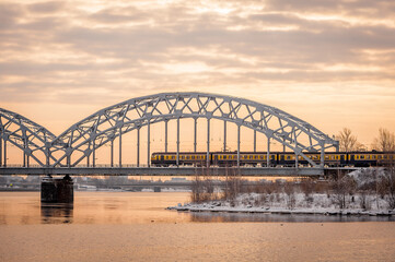 Electric train on the steel railway bridge at sunrise spring morning. Riga, Latvia.