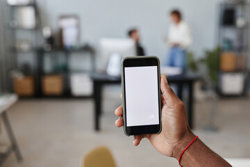 Close-up of man holding smart phone in his hand with empty screen while working at office