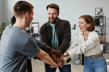 Successful business people holding hands and smiling during their teamwork at office