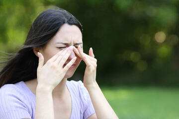 Asian woman scratching itchy eyes in a park