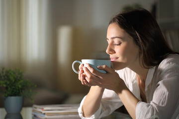 Relaxed woman smelling coffee in the morning at home