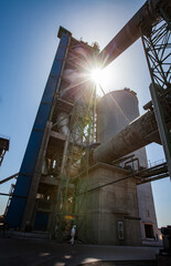 Silhouette of main cement tower, clinker kiln, tubes and silo. Bright sun direct in camera. Jambyl...