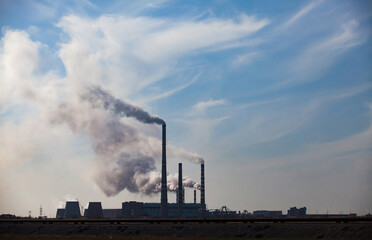 Fototapeta na wymiar Silhouette of Pavlodar thermal electric station with smoke against blue sky.