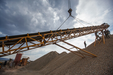 Workers assembling rock crushing machine. Using for gold ore shredding. Lifting metal girder. Mining and processing plant Altynalmas. Almaty region, Kazakhstan