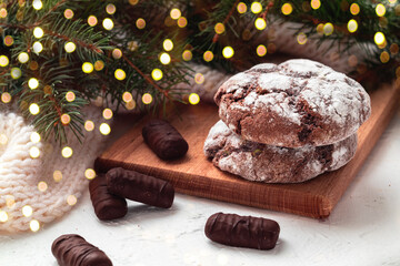 Two chocolate cookies and chocolade candy on a wooden board on a light background. Chocolate brownie on a blurred background. Side view. - Powered by Adobe