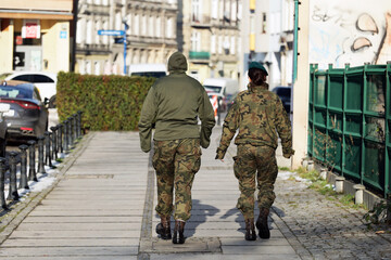 Młode dziewczyny w mundurach wojskowych idą przez miasto. - obrazy, fototapety, plakaty