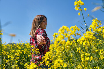 caucasian young woman enjoying in the middle of a field of yellow flowers. Rapeseed fields (Brassica napus) in spring