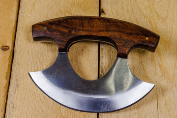 Close up of a Ulu knife with a wood handle on pine boards. Traditionally used by Inuit (Eskimo) women and is an all-purpose knife. 
 - obrazy, fototapety, plakaty
