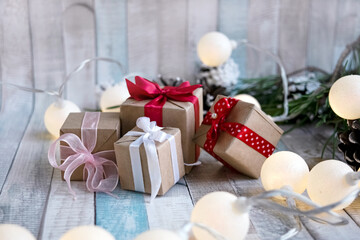 Fototapeta na wymiar Gift wrapping, Christmas decor and a garland of glowing lights on a wooden table. Festive concept. Gifts for Christmas and New Year.